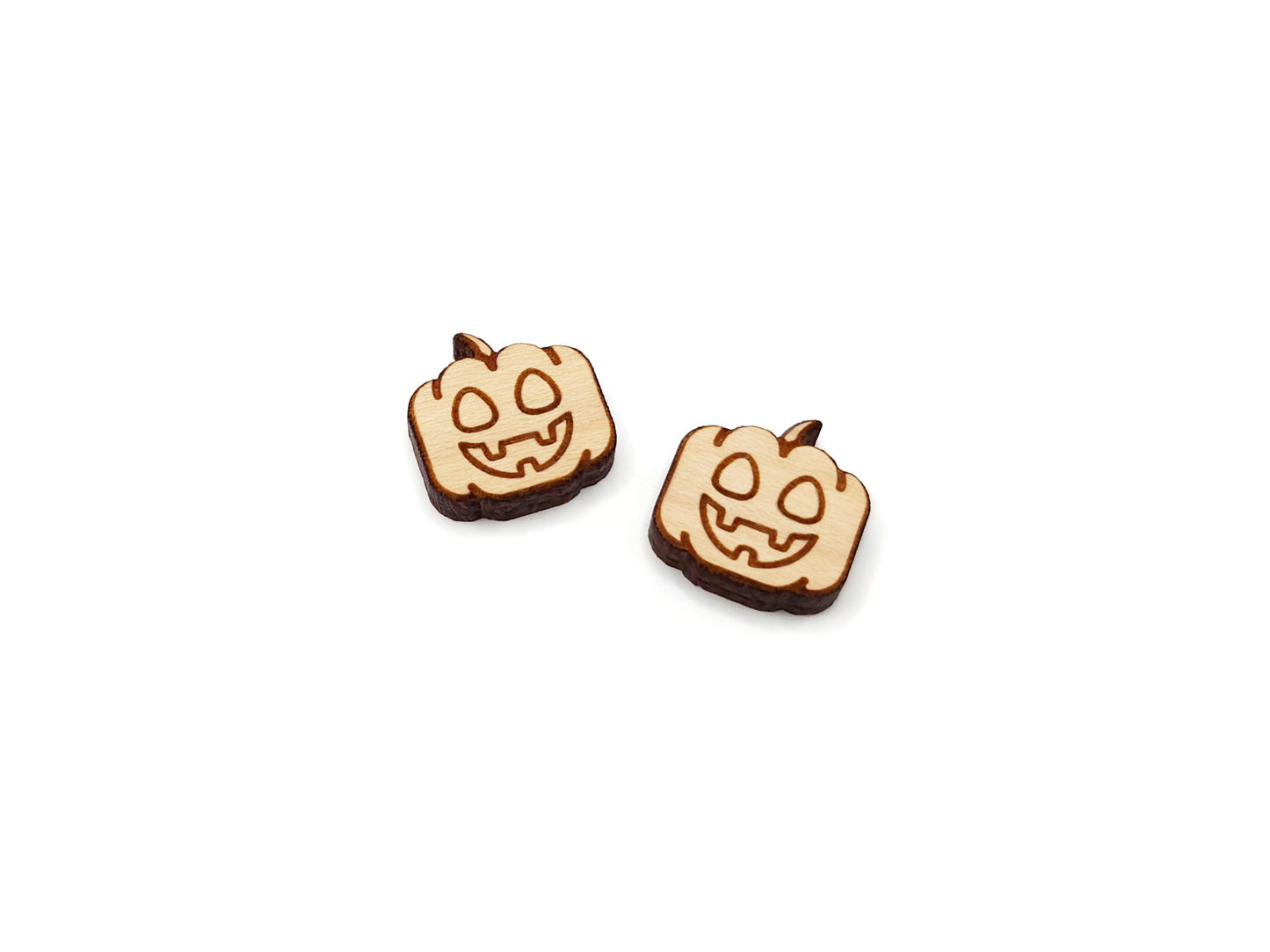 a pair of wooden cabochon earring blanks cut and engraved to look like a happy jack-O-lantern