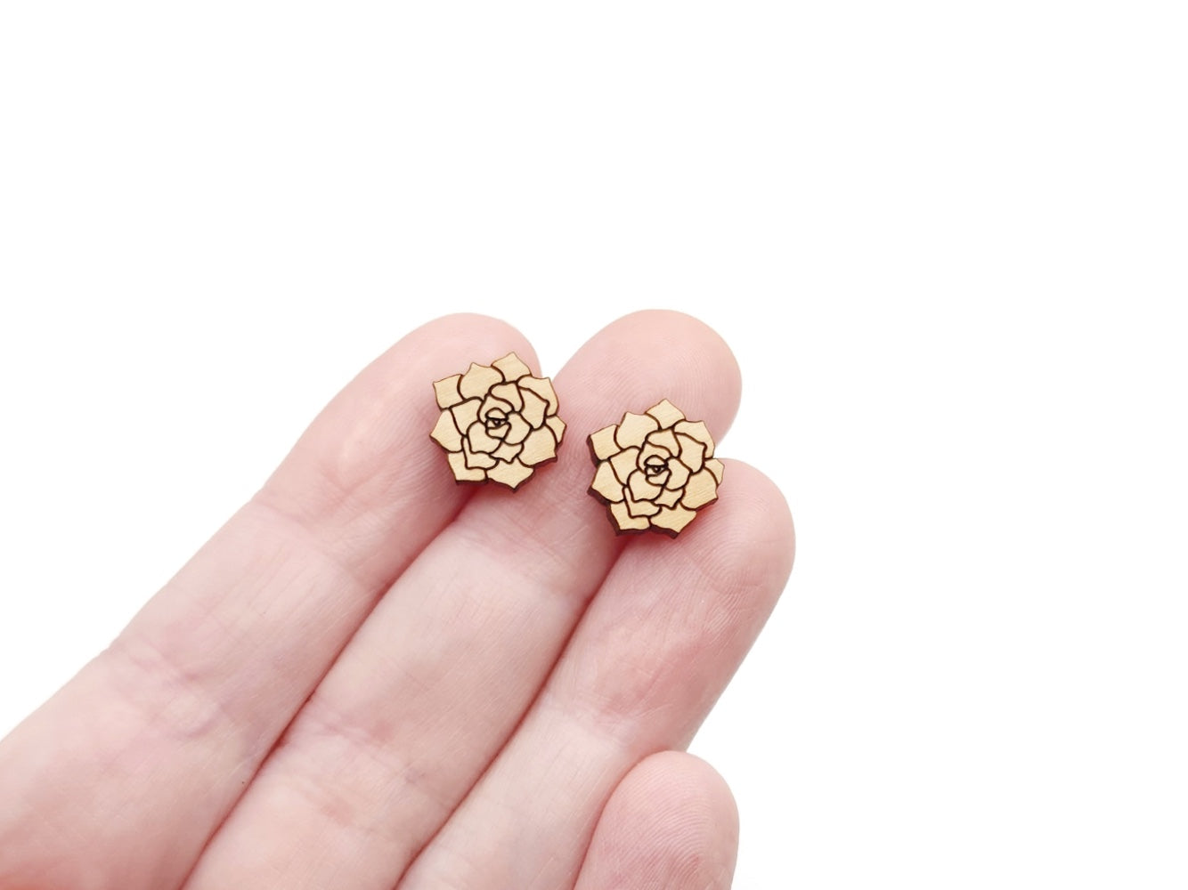 a hand holding a pair of gold earrings