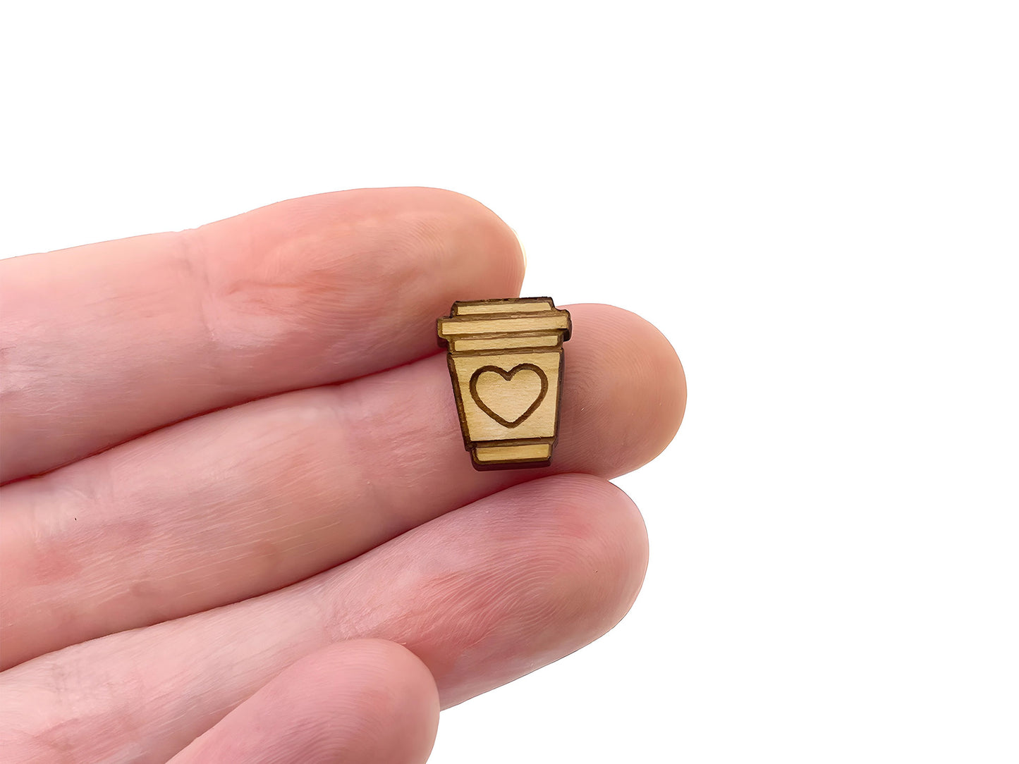 a hand holding a wooden ring with a heart on it