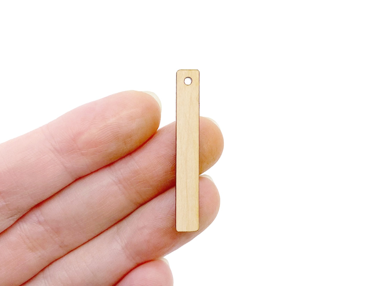 a person holding a bar-shaped wood or acrylic jewelry charm blank