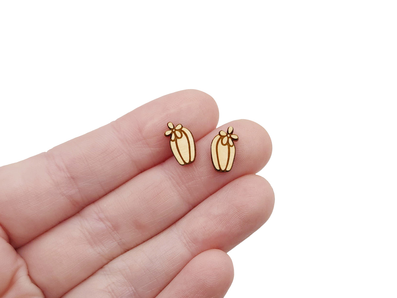 a hand holding a pair of wooden cabochon stud earring blanks cut and engraved to look like a blooming cactus