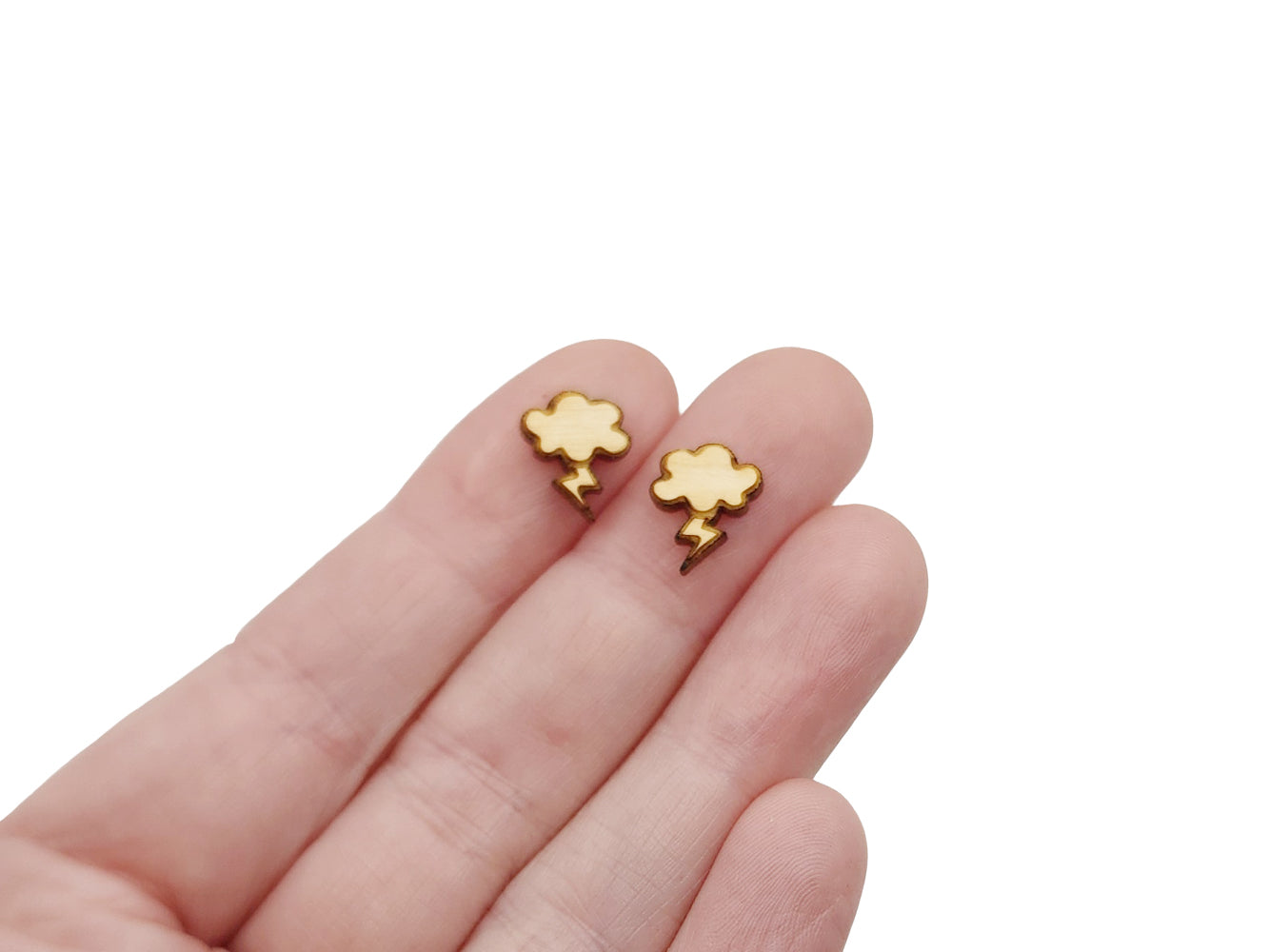 a hand holding a pair of gold earrings