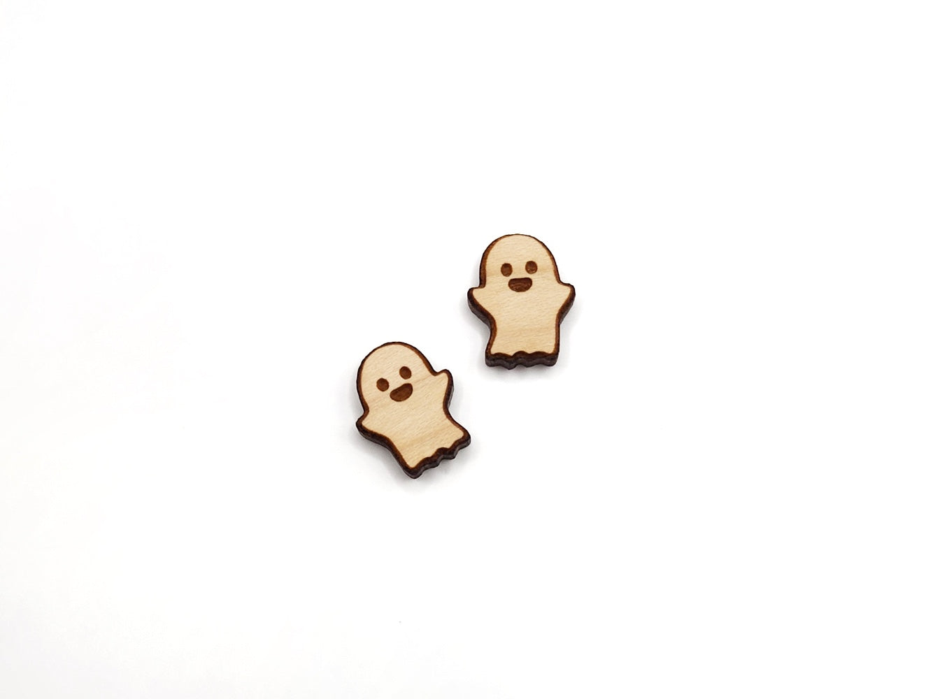 a pair of wooden cabochon stud earring blanks cut and engraved to look like a ghost