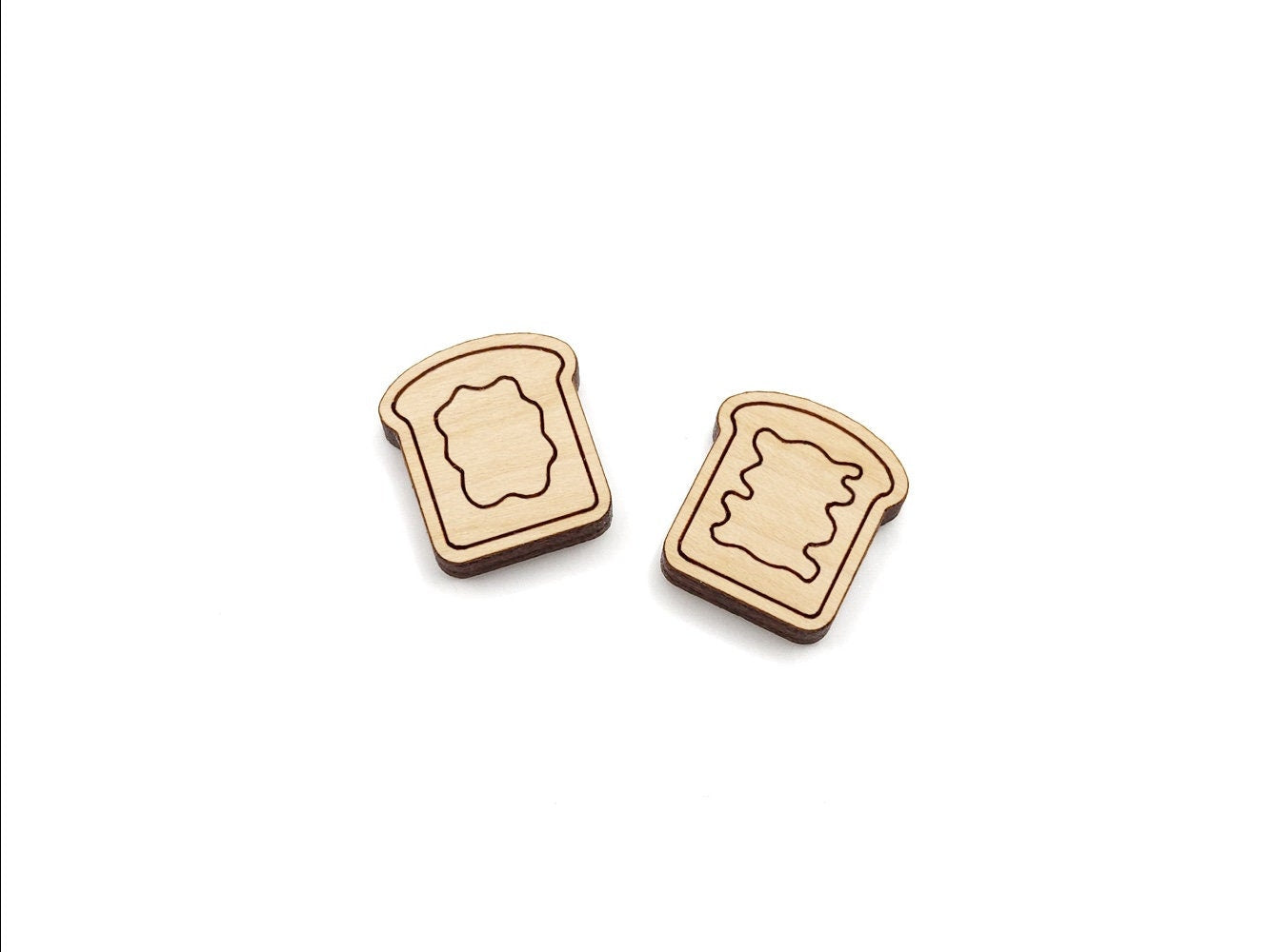 a pair of wooden cabochon stud earring blanks cut and engraved to look like pieces of bread with peanut butter and jelly