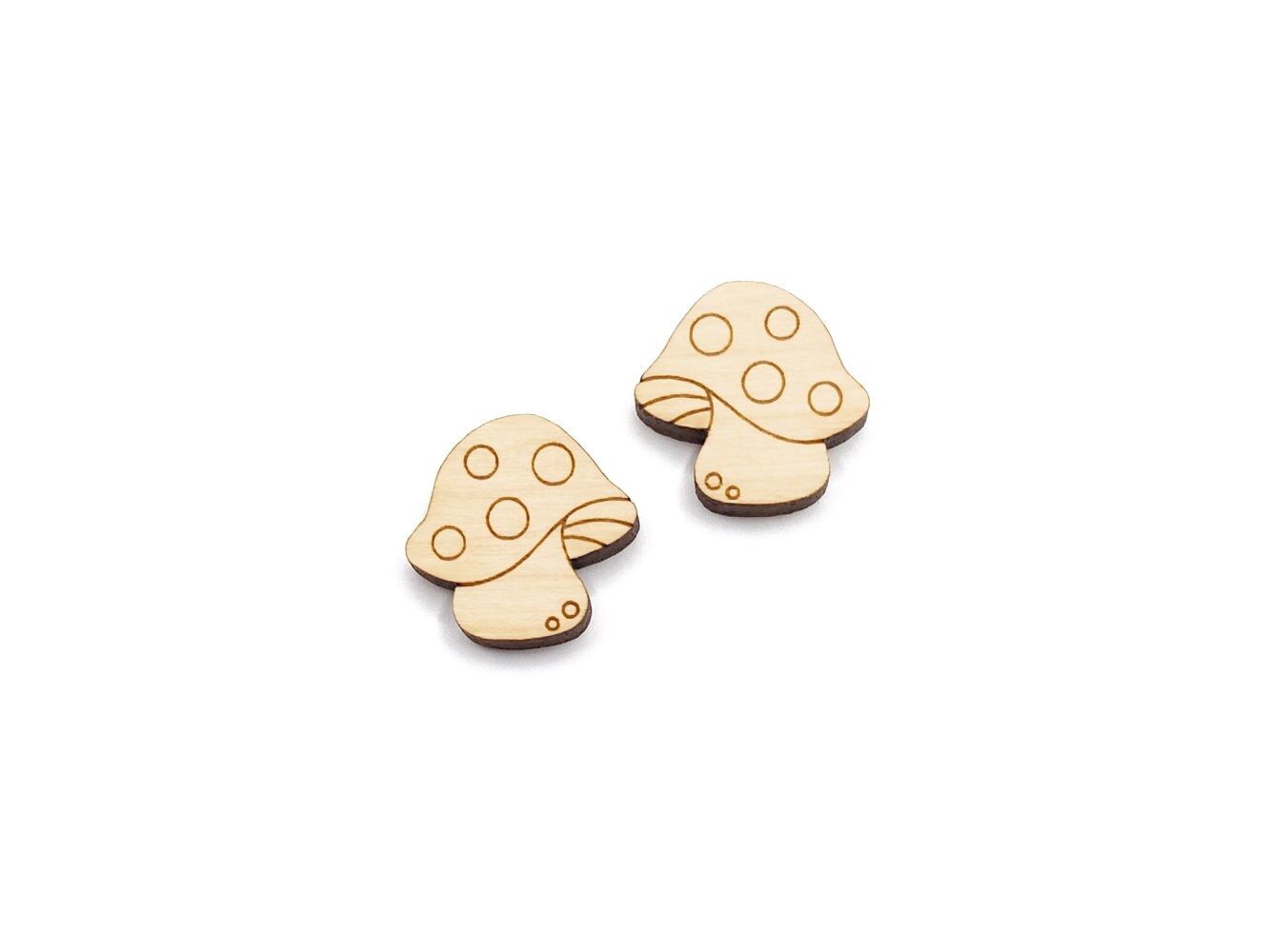 a pair of wooden cabochon stud earring blanks cut and engraved to look like spotted mushrooms