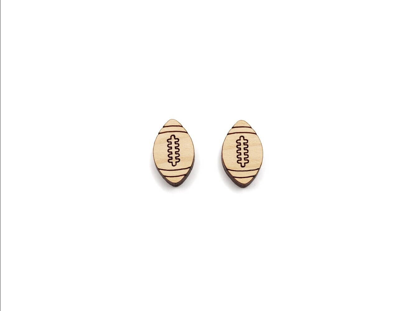 a pair of wooden cabochon stud earring blanks cut and engraved to look like footballs
