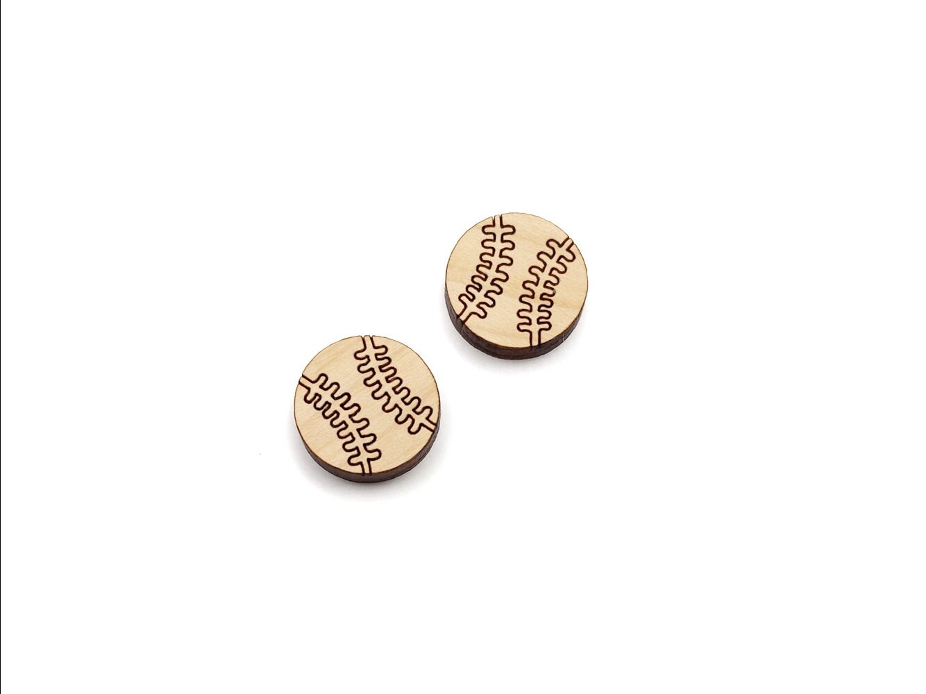 a pair of wooden cabochon stud earring blanks cut and engraved to look like baseballs