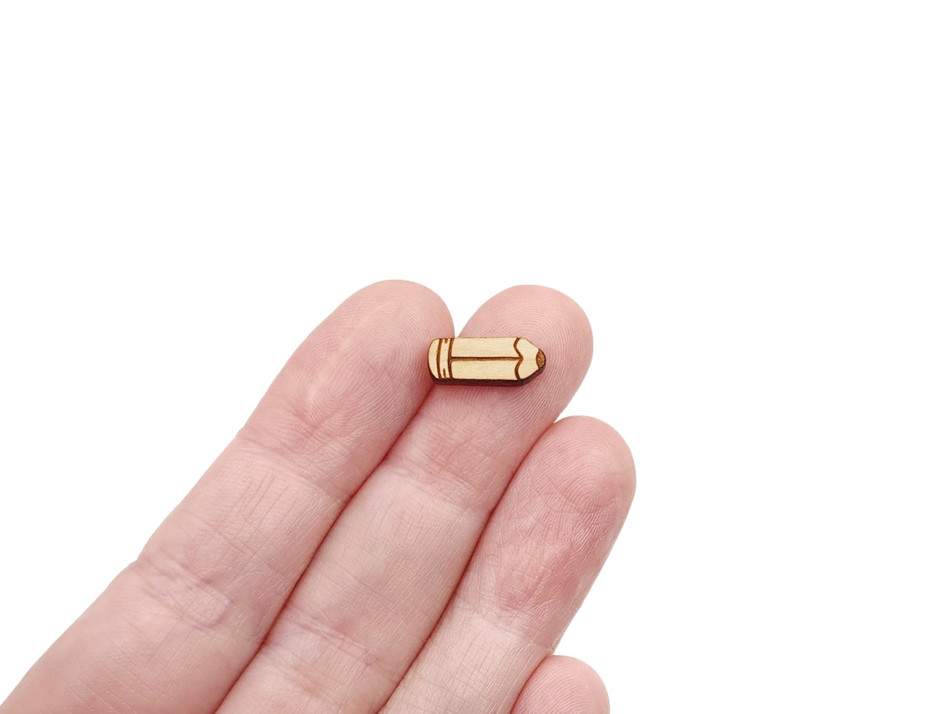 a person's hand holding a pair of wooden cabochon earring blanks cut and engraved to look like a pencil