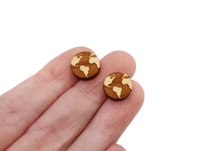 a hand holding a pair of small wooden earrings
