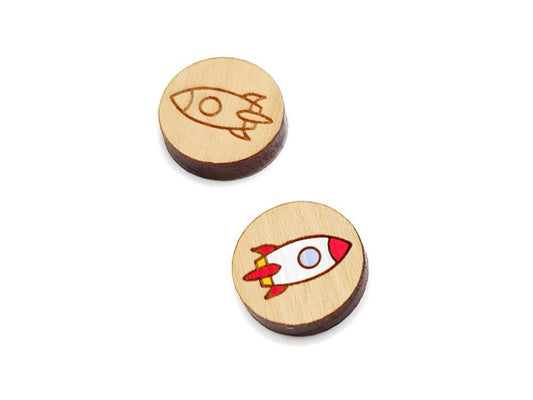 a pair of round wooden cabochon earring blanks engraved with a rocket ship design