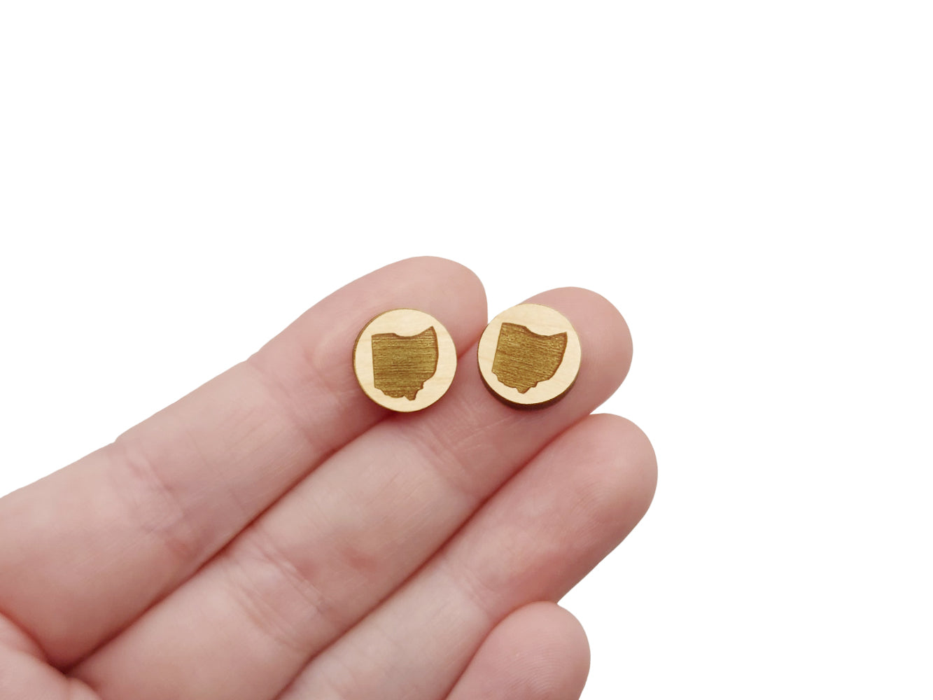 a hand holding a pair of round wooden cabochon earring blanks engraved with the State of Ohio