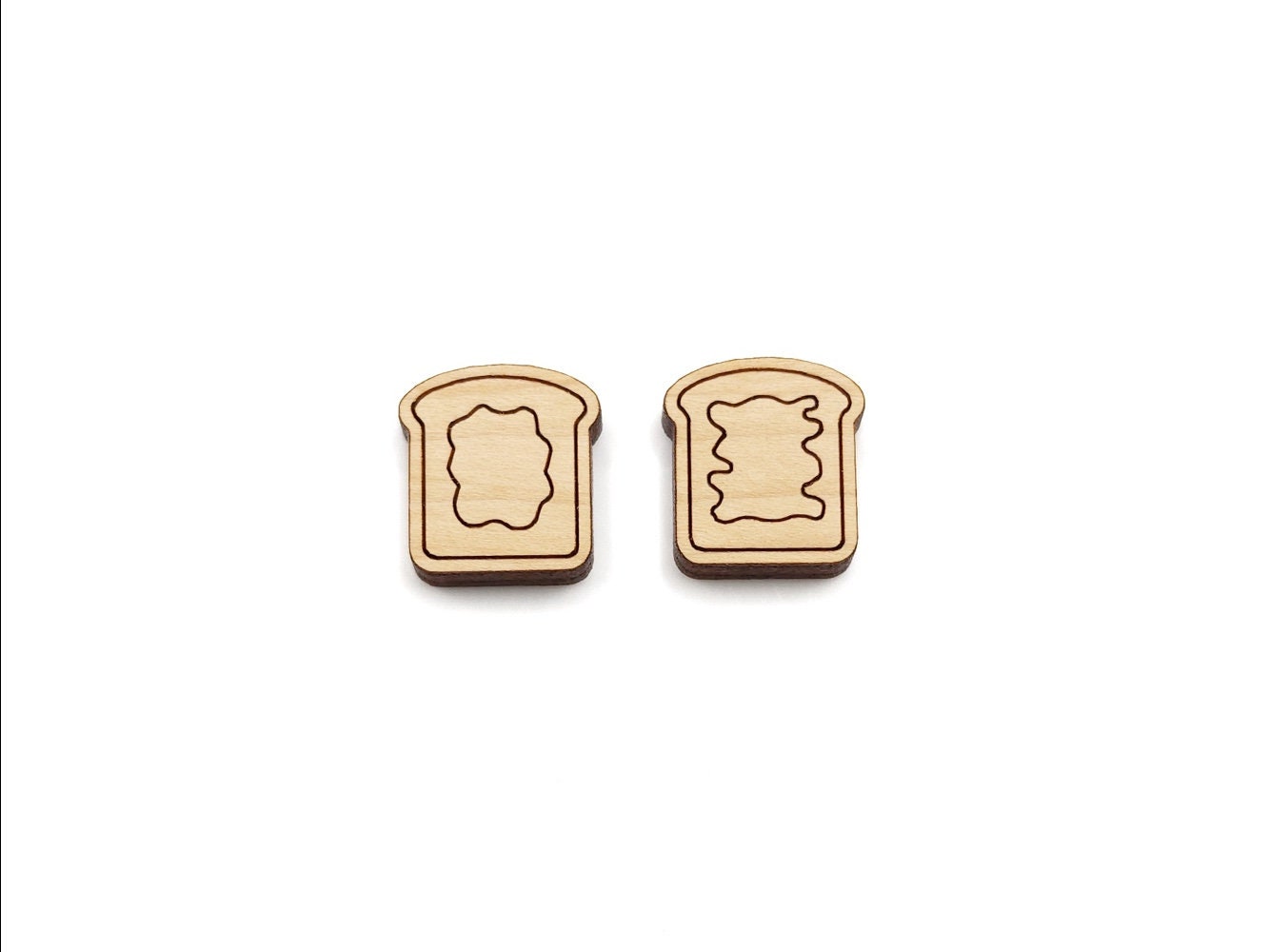 a pair of wooden cabochon stud earring blanks cut and engraved to look like pieces of bread with peanut butter and jelly